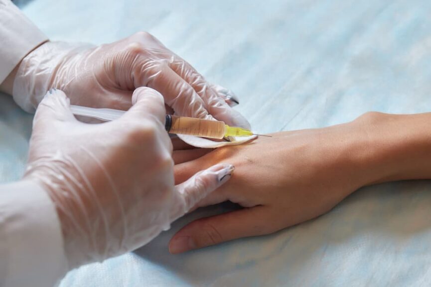 A medical professional in white gloves administering a syringe injection into a patient's hand, illustrating common procedures analyzed to answer is stem cell therapy safe.